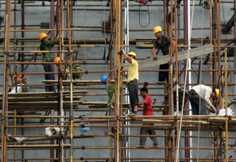 Labourers work on a scaffolding at a construction site in Wuhan