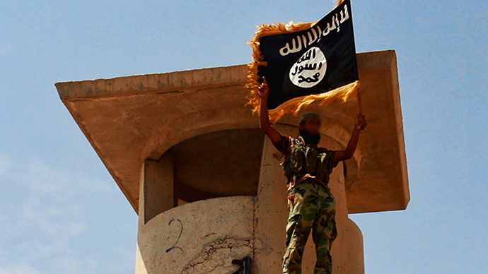 Militant of the Islamic State of Iraq and the Levant (ISIL) posing with the trademark Islamists flag