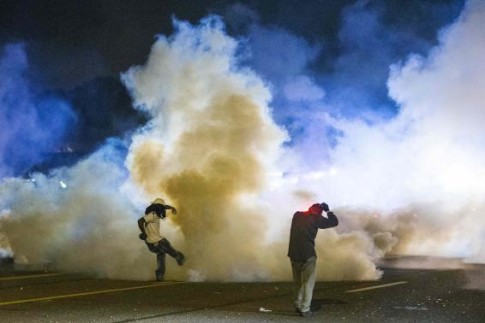 A protester kicks a tear gas canister back towards police after protests in reaction to the shooting of Michael Brown turned violent near Ferguson, Missouri