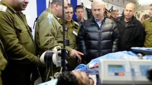 Israeli Prime Minister Benjamin Netanyahu visits a militant wounded in Syria at a field hospital in northern Israel, February 18, 2014.