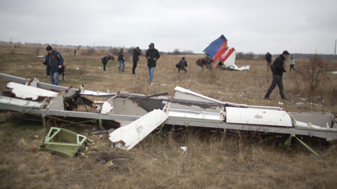 Journalists look at parts of the Malaysia Airlines plane Flight MH17 as Dutch investigators (unseen) arrive at the crash site near the Grabove village in eastern Ukraine